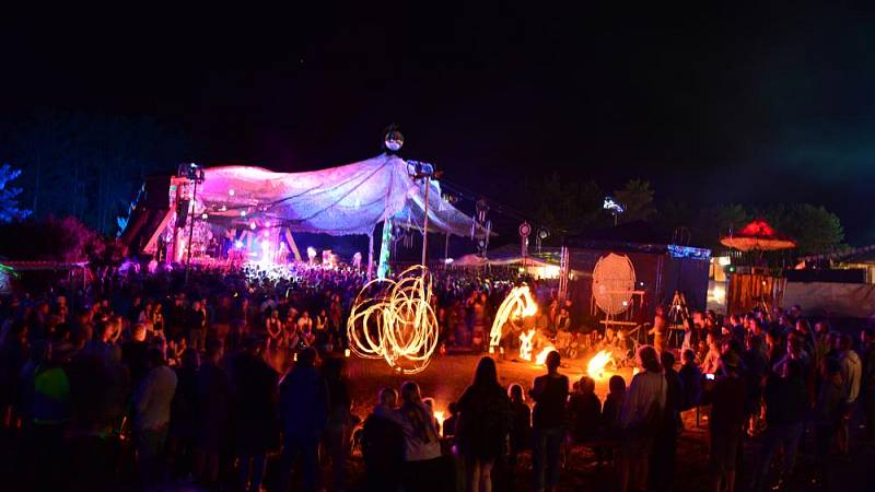 Besucher bestaunen die Show der Feuerkünstler vor der farbenfroh beleuchteten Sandpalast-Bühne