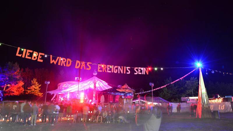Der Drahtseilspruch 'Liebe wird das Ereignis sein' prangt über dem gut besuchten Festivalgelände mit Blick auf die kunterbunten Bühnen